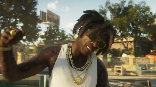 A Black man with dreadlocks, yellow sunglasses, gold grills, and multiple gold chains…