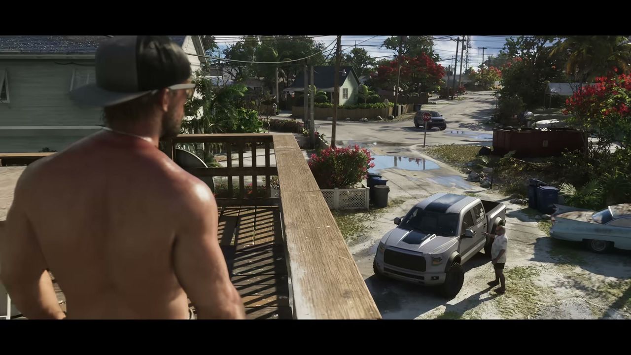 A shirtless man with a baseball cap stands on a wooden balcony overlooking a residential street…