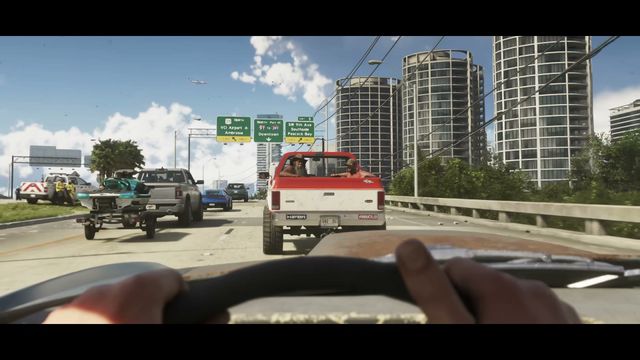 A first-person view from a car shows a multi-lane highway with traffic, including a red pickup truck with…