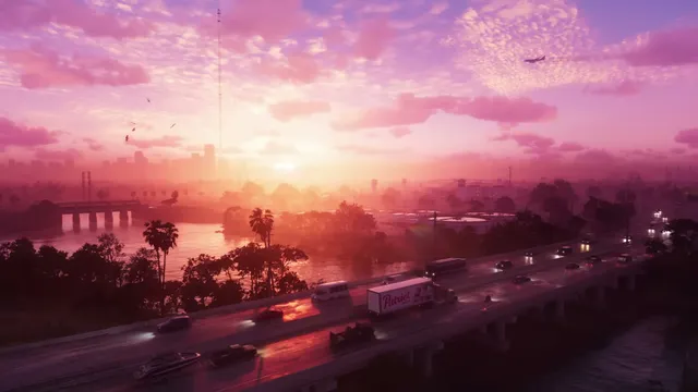 An aerial view captures a vibrant pink and purple sunrise or sunset over a city skyline with a multi-lane…