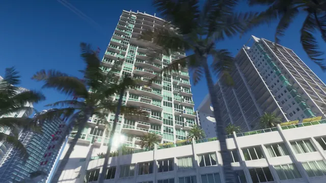A low-angle view captures several modern high-rise buildings with numerous balconies, framed by palm trees…
