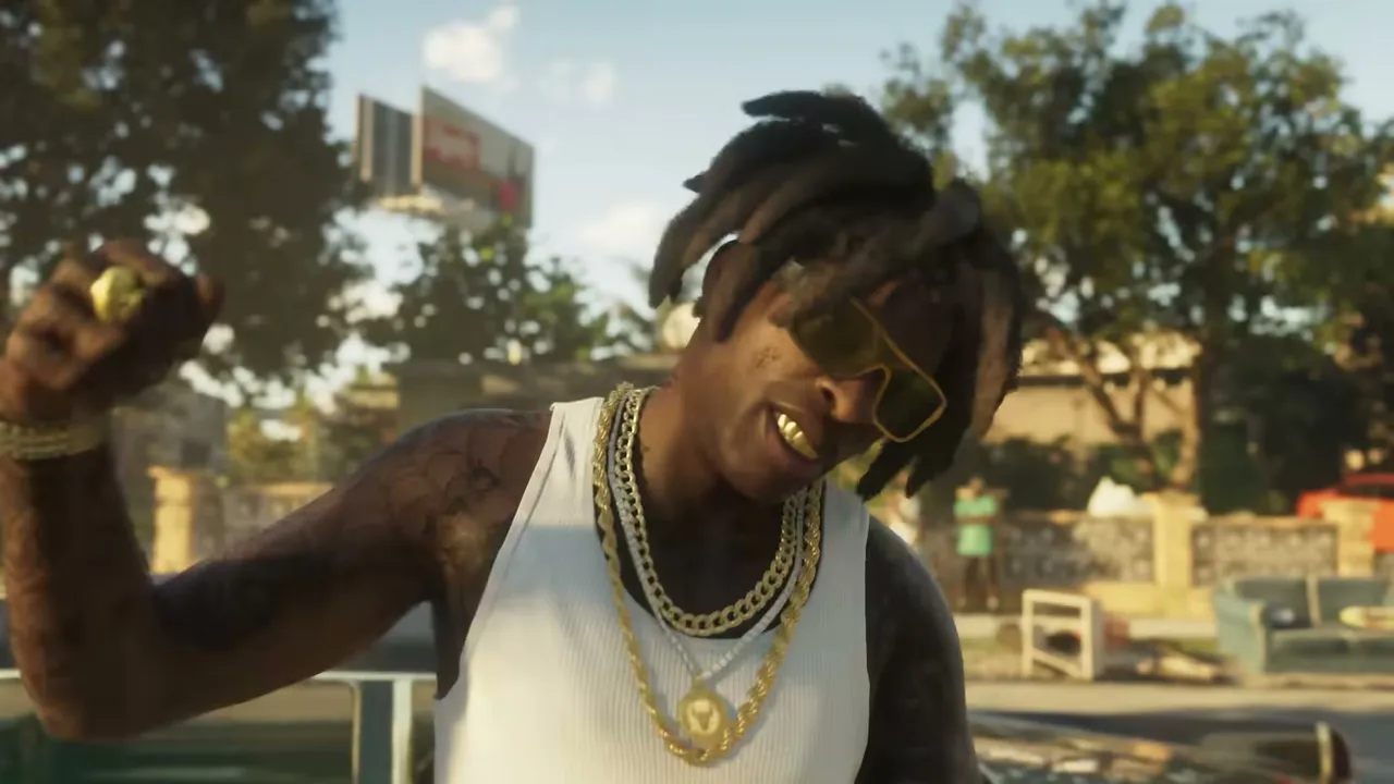 A Black man with dreadlocks, yellow sunglasses, gold grills, and multiple gold chains smiles at…