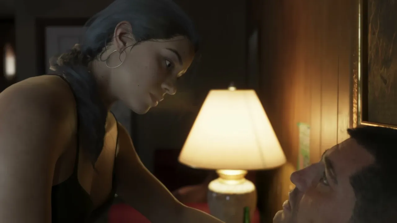 Lucia Caminos looks down intently at Jason Duval, who is lying down, in a dimly lit room with a…