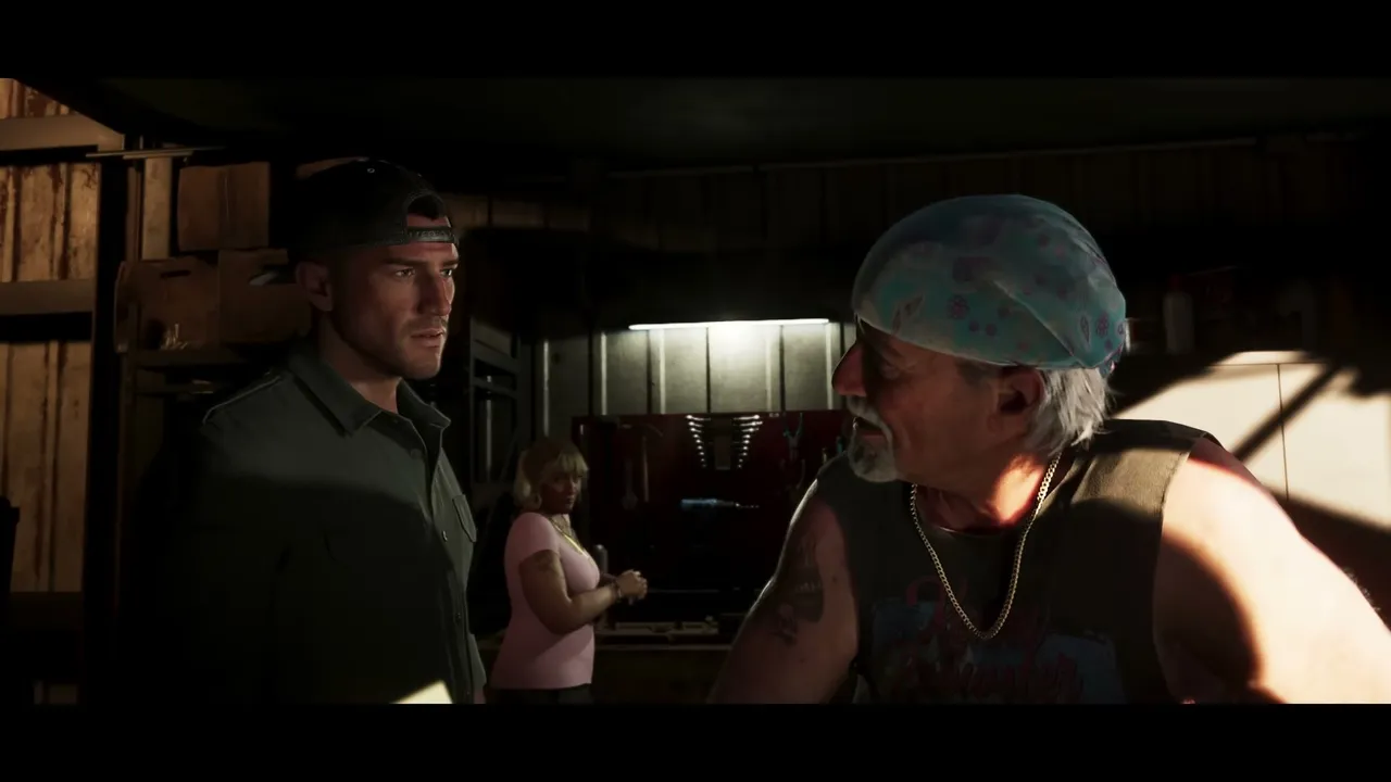 Jason Duval stands in a dimly lit garage or workshop, looking at an older man with a bandana and…