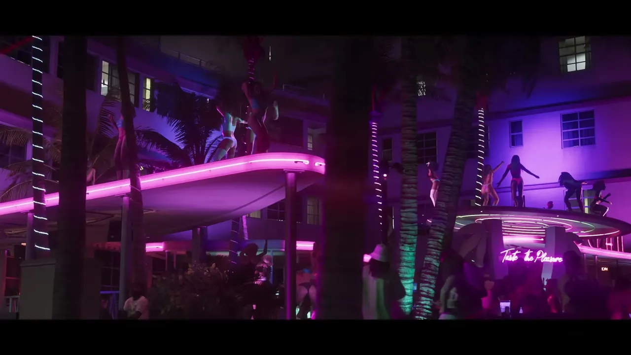 Multiple women are seen dancing on the ledges and balconies of a neon-lit building at night…