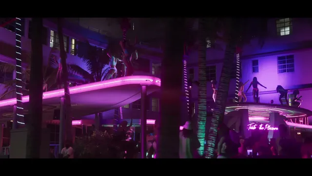 Multiple women are seen dancing on the ledges and balconies of a neon-lit building at night, surrounded by…